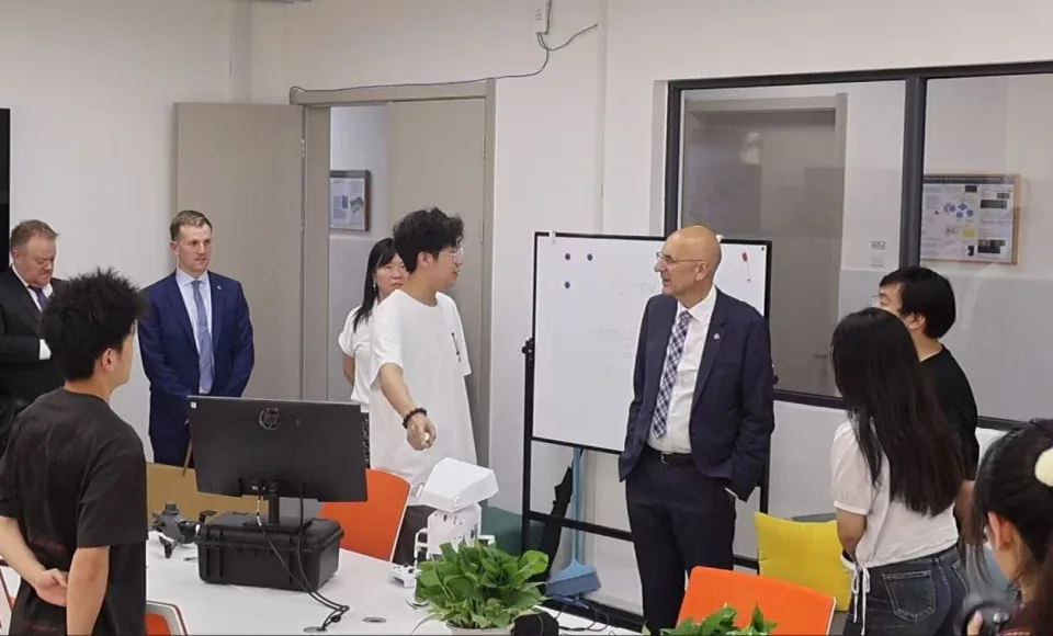 来访交流现场,学生在项目展示台前向来宾介绍机器人